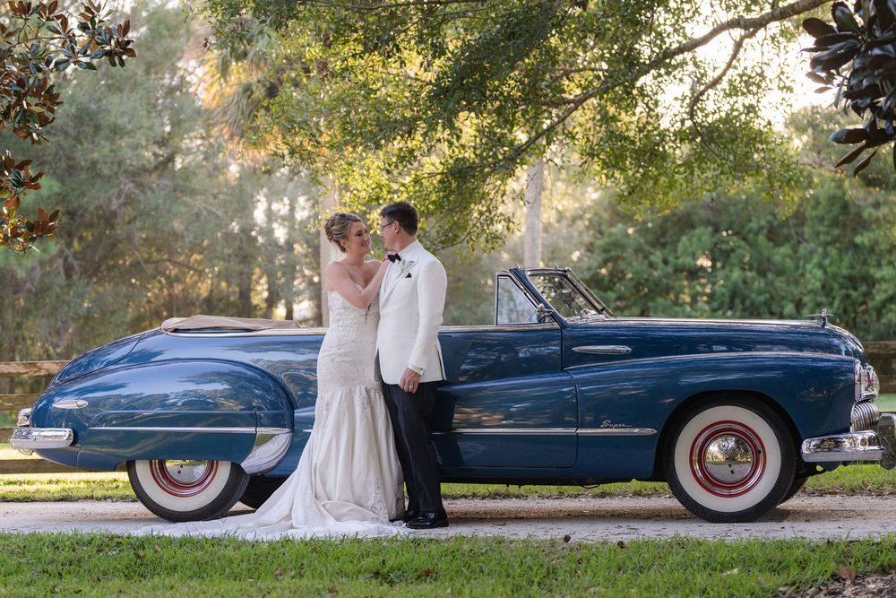 Bride and groom standing beside a vintage blue convertible at Magnolia Manor in Vero Beach, FL
