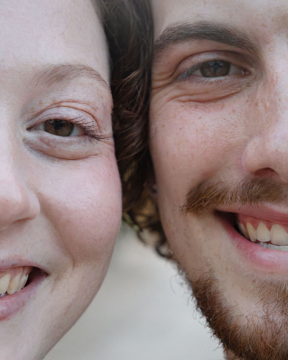 A close-up portrait of a smiling couple with faces side by side showing genuine happiness.