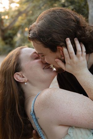 A passionate couple sharing a kiss outdoors in warm golden natural lighting.