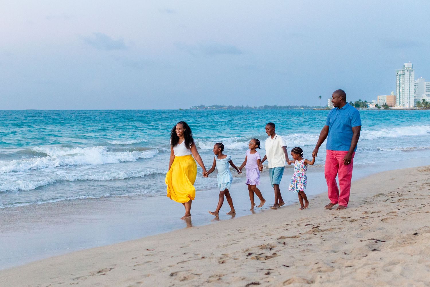 Family portrait. Mom, dad, and four kids holding hands and walking on the beach in Isla Verde, Carolina, Puerto Rico.
