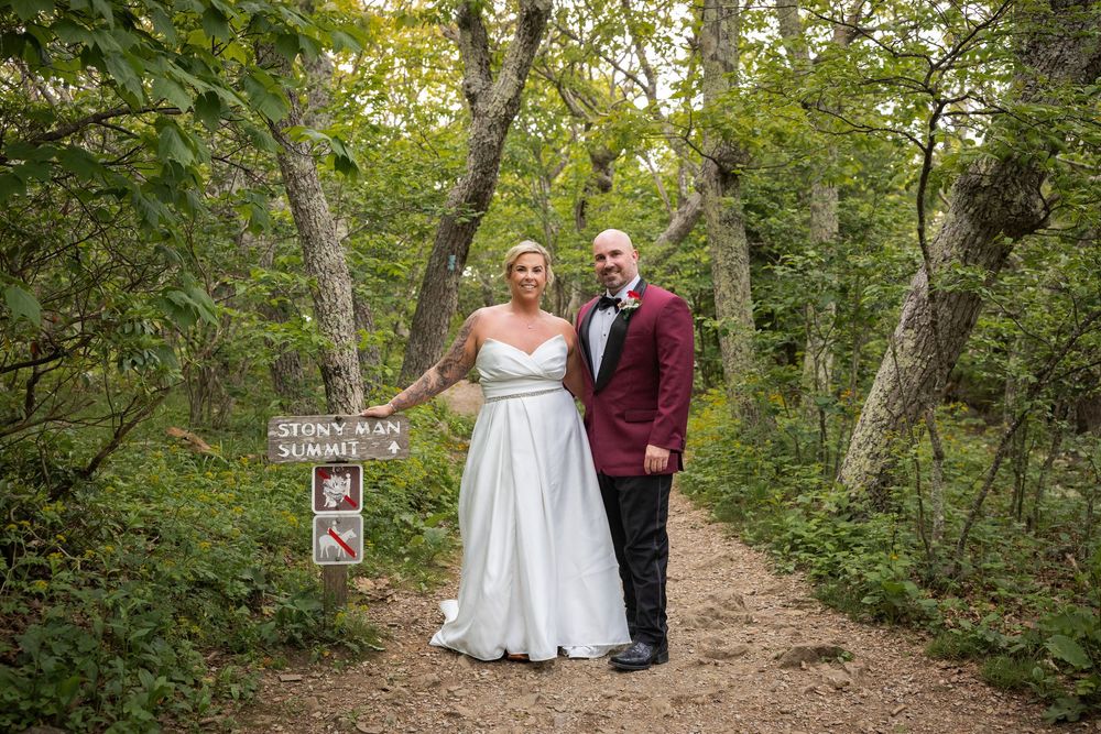 Bride and groom pose on a wooded trail near a Stony Man Summit sign during their elopement in Shenandoah National Park.