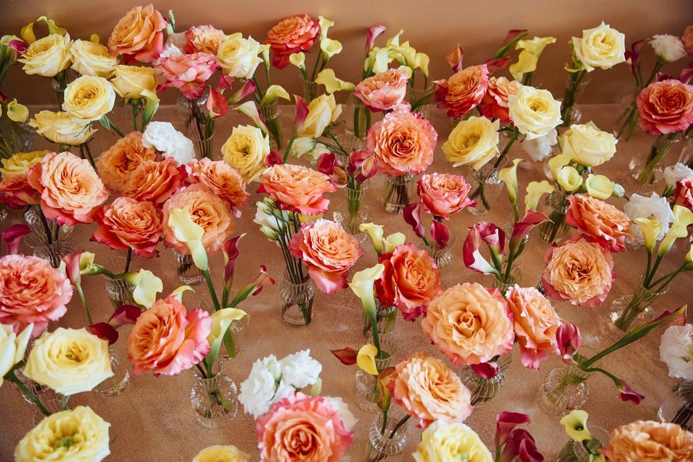 Colorful arrangement of orange, pink, yellow, and white roses displayed on a brown paper surface.