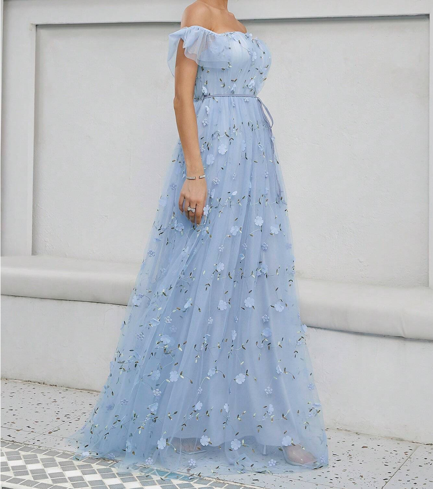Elegant off-shoulder light blue floral tulle maxi dress with A-line silhouette and delicate 3D flower embellishments.