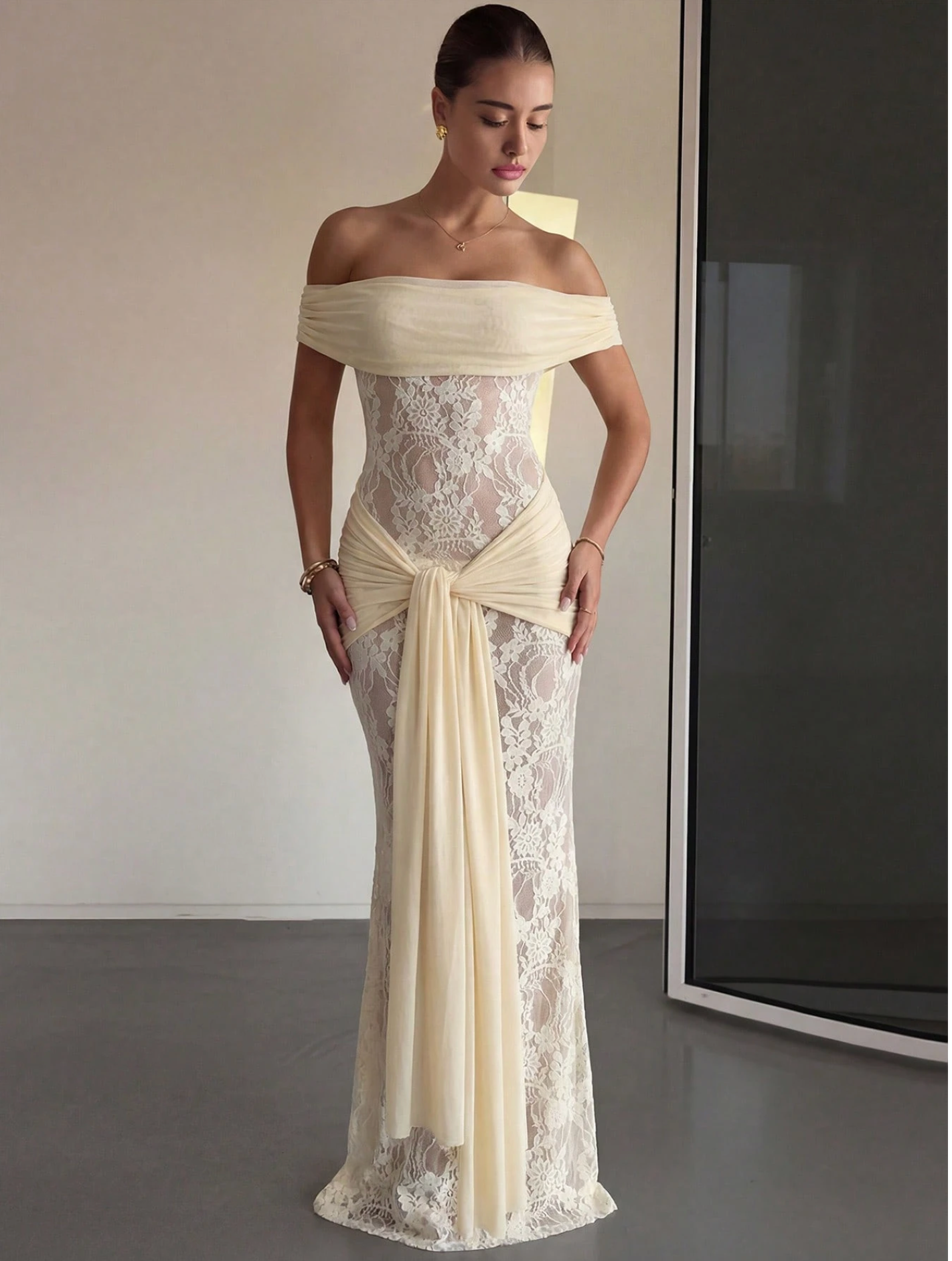 Elegant off-shoulder cream lace mermaid gown with chiffon drape and bow detail.