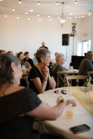 Guests seated at tables during a wedding reception under string lights in an elegant venue.