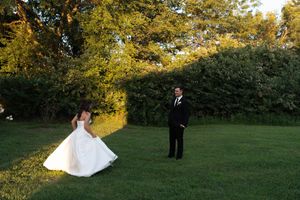 Bride and groom share a first look moment on a lush green lawn at golden hour.