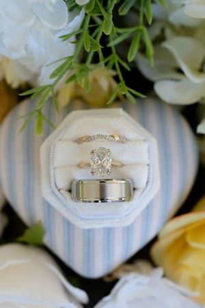 Three wedding rings displayed in an octagonal velvet ring box surrounded by white and yellow flowers.