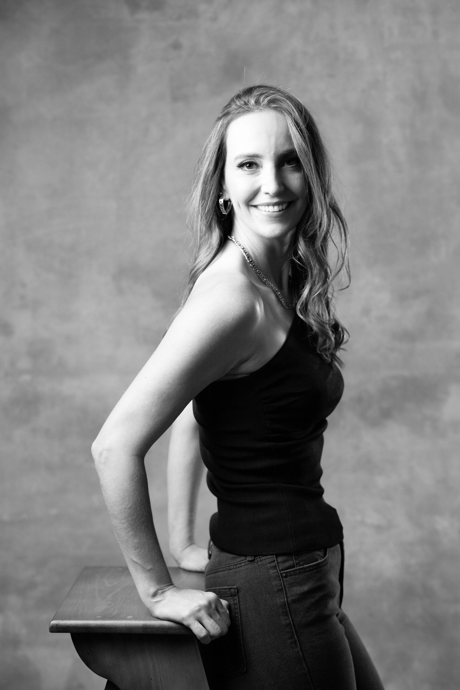 Black and white studio portrait showing relaxed pose against textured background.