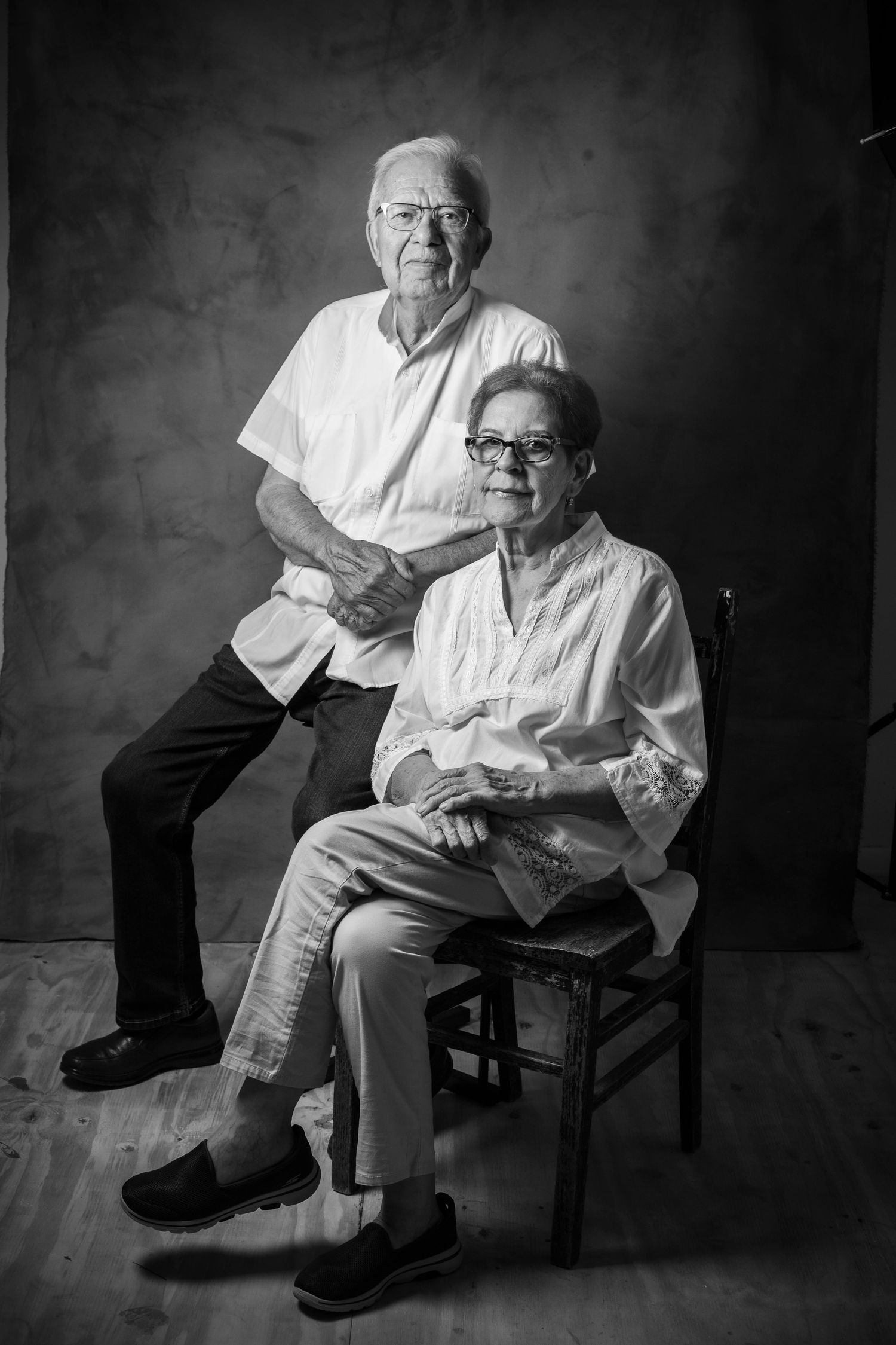 Black and white portrait of two seniors seated together in a classic studio setting.