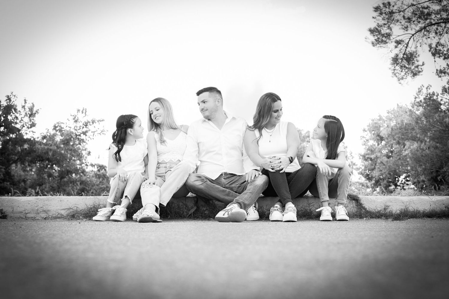 Black and white outdoor group photo of five people sitting together on grass.