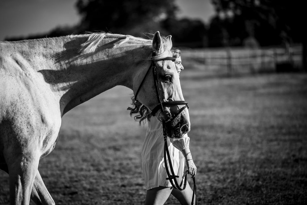 Frau und Pferd im Profil beim gemeinsamen Laufen, fotografiert in Schwarz-Weiß – ein inniger Moment zwischen Mensch und Tier.