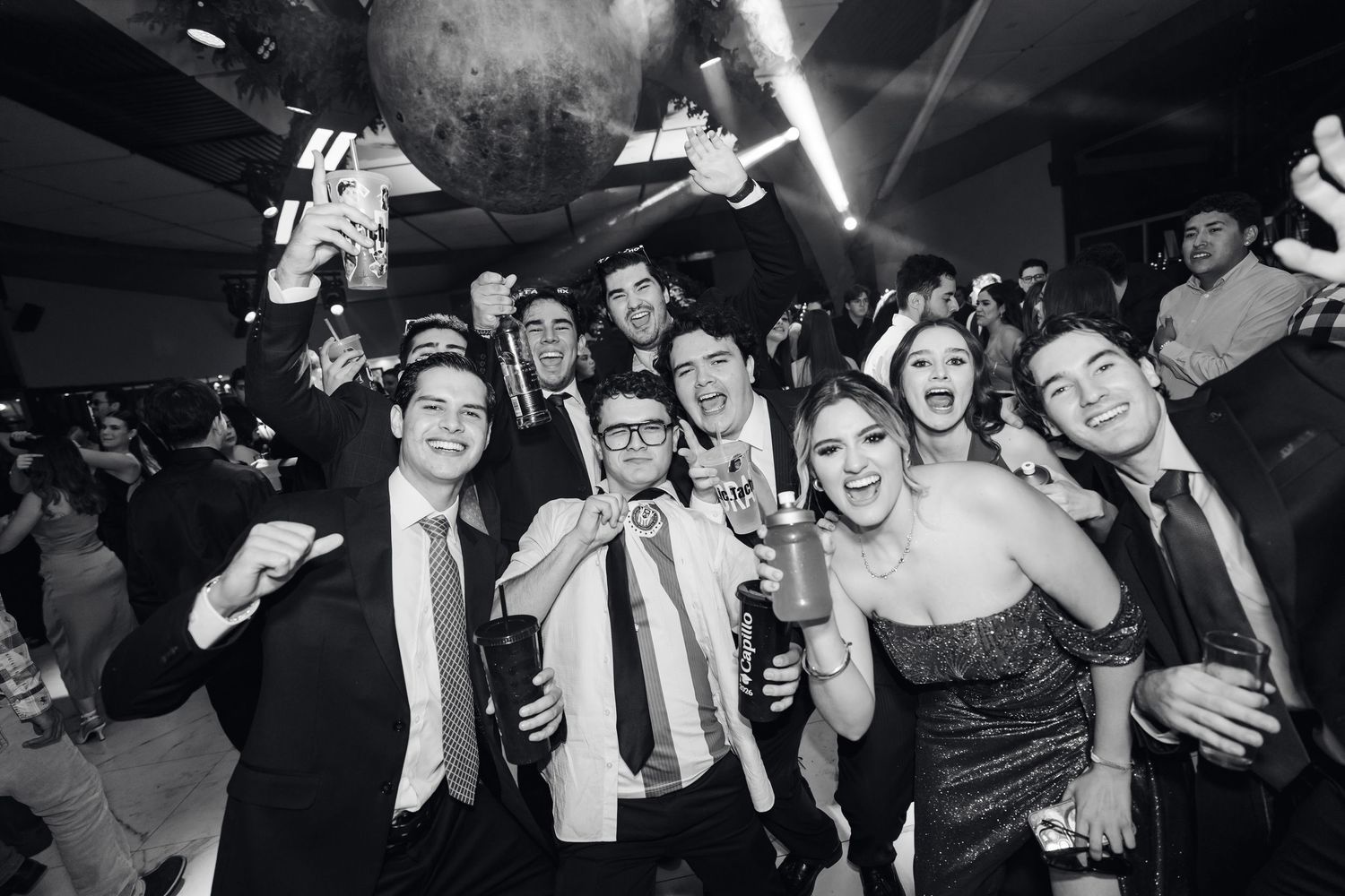 Celebratory group photo with people in formal attire raising hands in excitement.