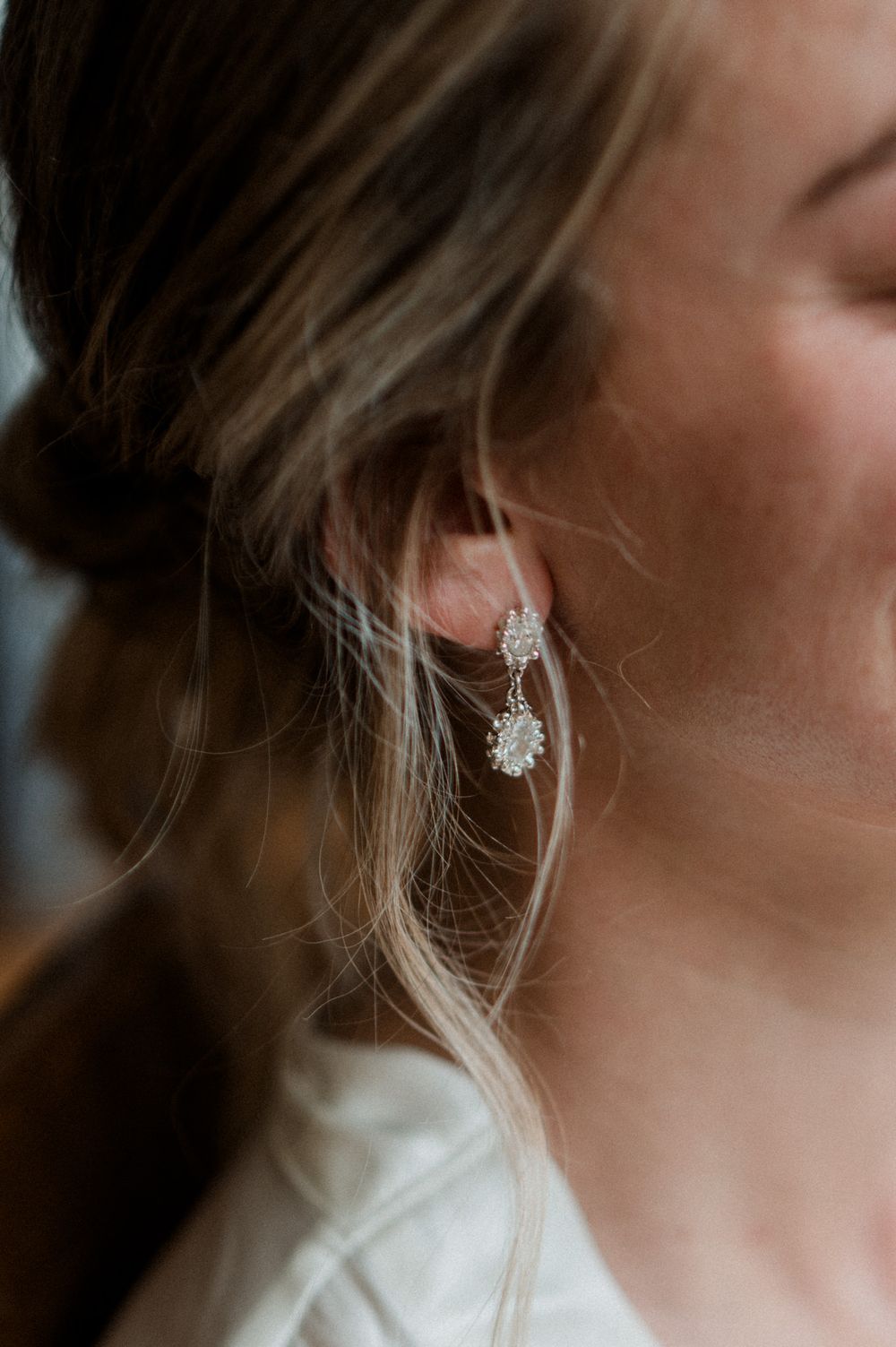Close-up of a woman wearing elegant silver crystal drop earrings, perfect for bridal or formal occasions.