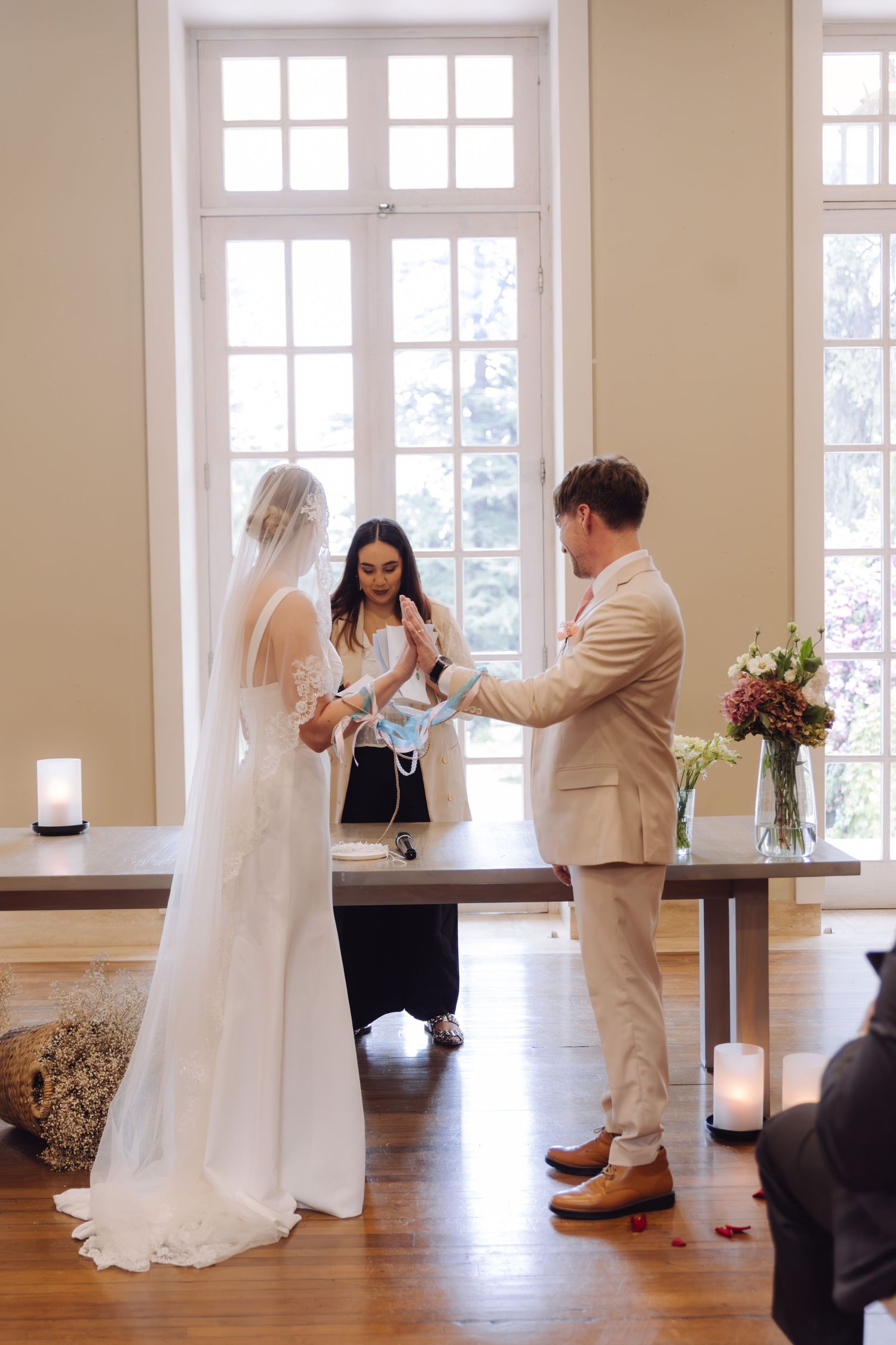 Bride and groom exchange rings during candlelit wedding ceremony with officiant.