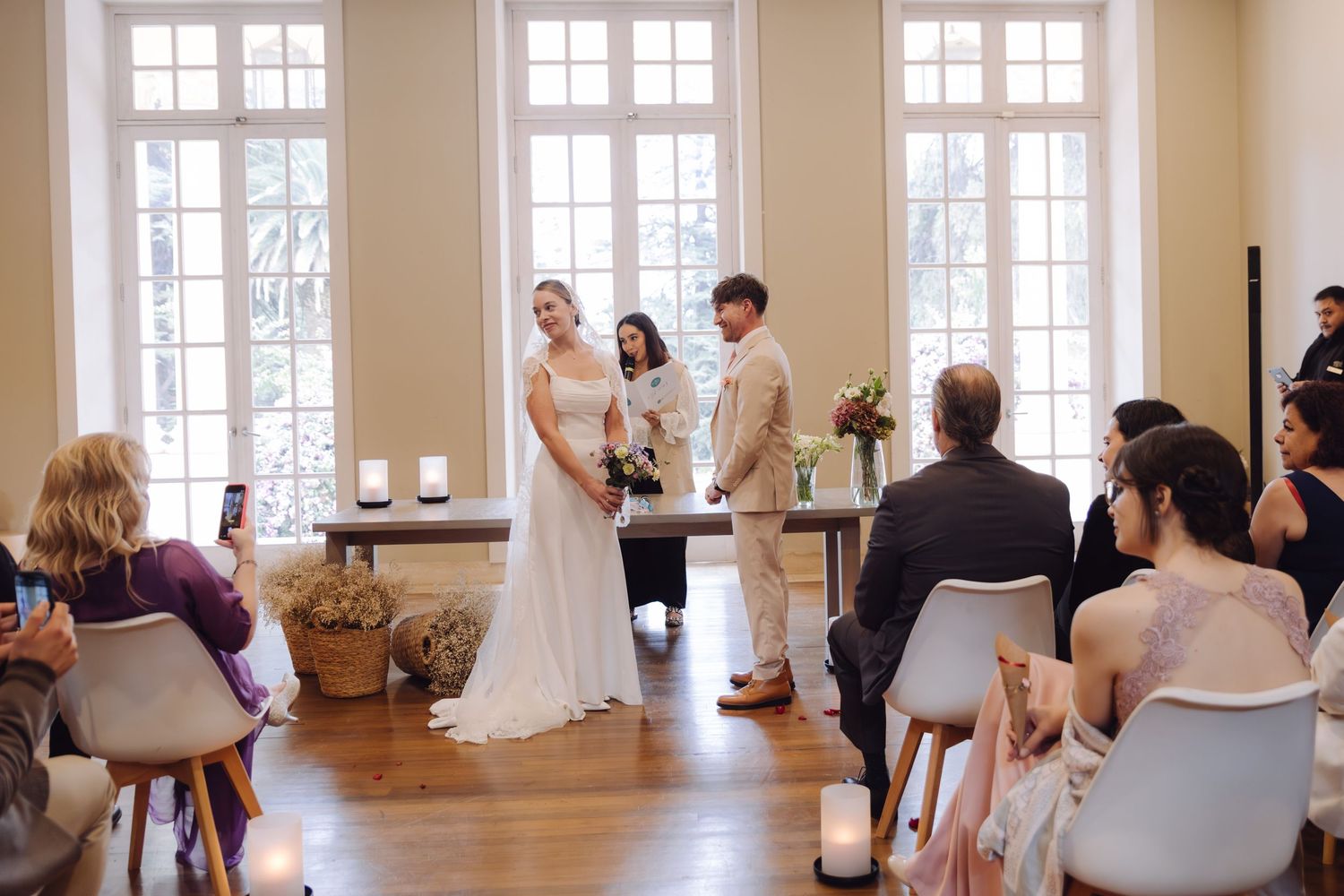 Bride and groom stand at altar during elegant indoor wedding ceremony with guests.