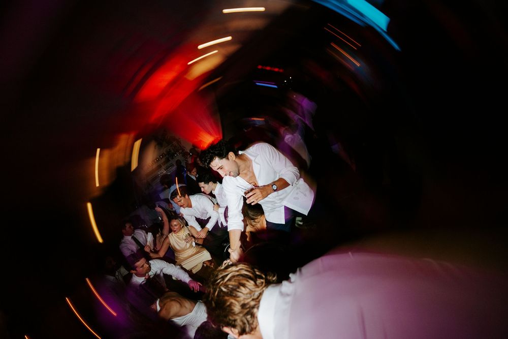 Aerial view of wedding reception dance floor with colorful spinning lights and guests celebrating.
