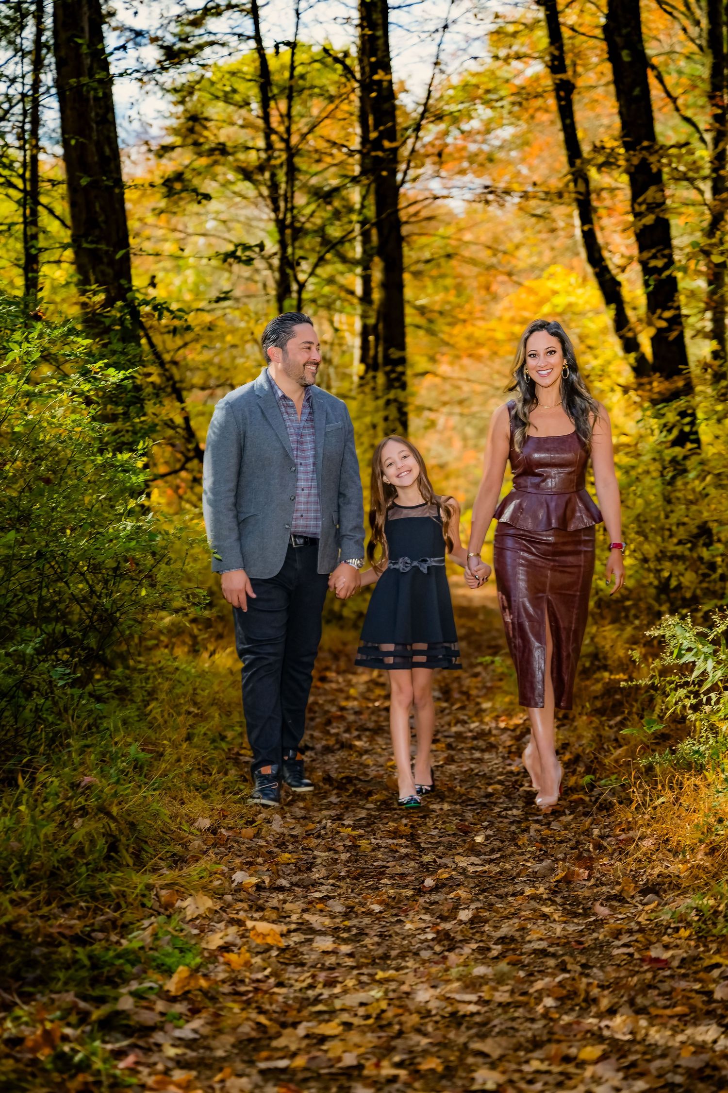 Family of four poses in lush green backyard garden, two seated in Adirondack chairs, two standing behind them.