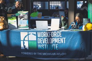 Workforce Development Institute booth powered by Michigan AFL-CIO with staff at tables and laptops at an event.