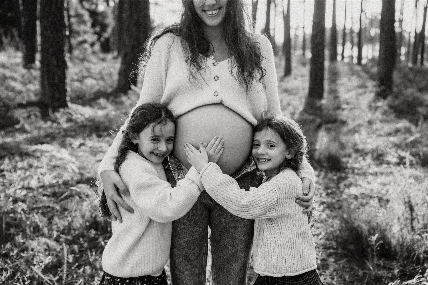 Black and white photo series showing joyful family moments outdoors in a forest setting.