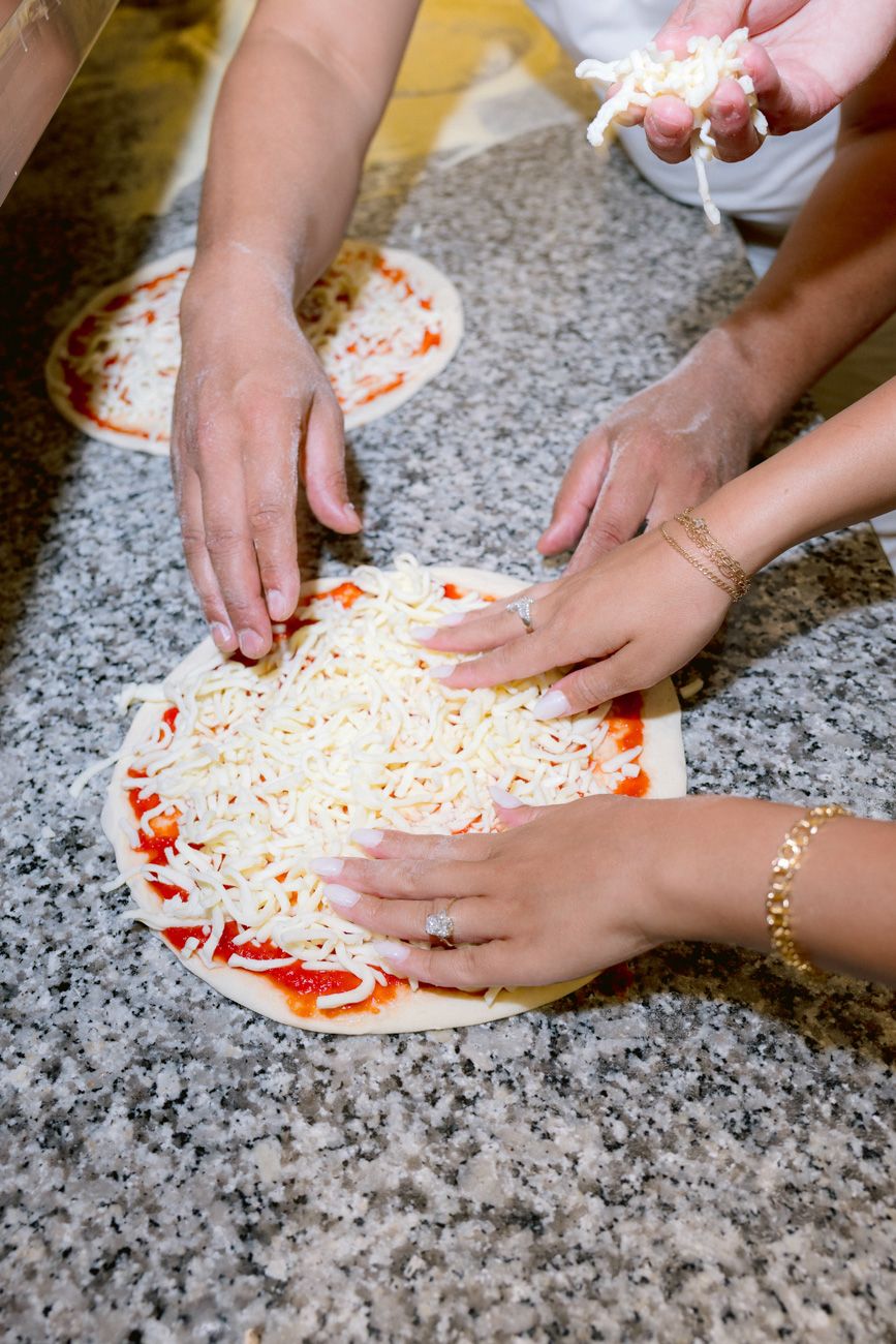Bride and groom making pizza at the welcome party of their three-day destination wedding on the shores of Lake Garda. Solidea Events