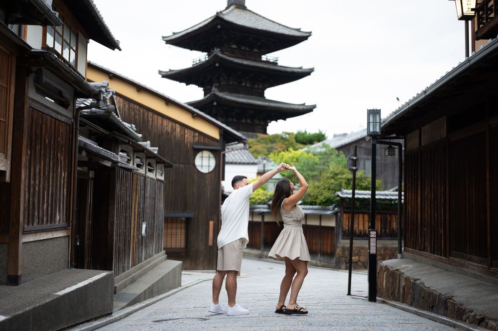 Couple dances together on a quiet Kyoto street with traditional wooden buildings and the Yasaka Pagoda rising in the background.