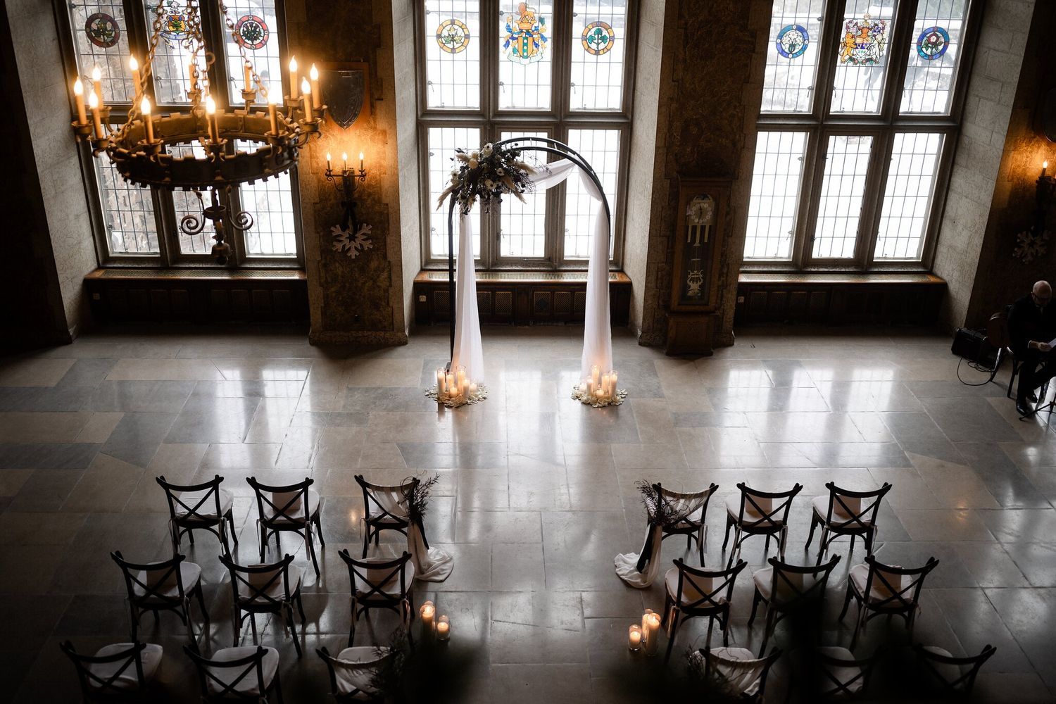 Overhead view of a Fairmont Banff Springs Christmas wedding ceremony with chandelier, draped arch and stained glass