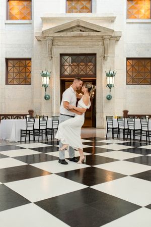 Bride and groom sharing a romantic dip kiss on a black and white checkered dance floor.