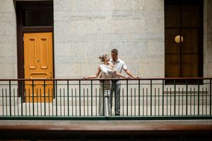 Wedding couple sharing a tender embrace on a balcony with iron railings outside a historic building.
