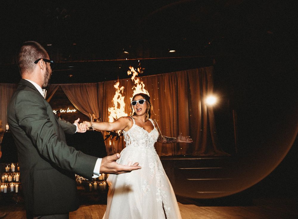 Bride and groom in sunglasses sharing a fiery first dance with flames behind them at the reception