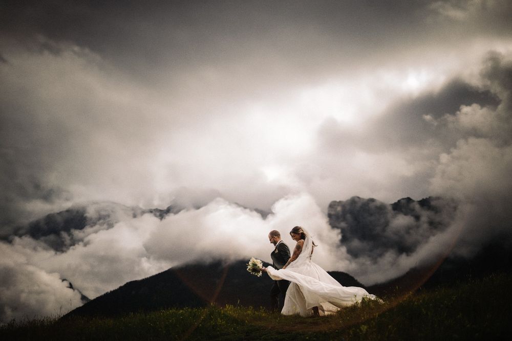 Groom dipping his bride for a kiss above a sea of clouds on a mountaintop, by a Canmore wedding photographer