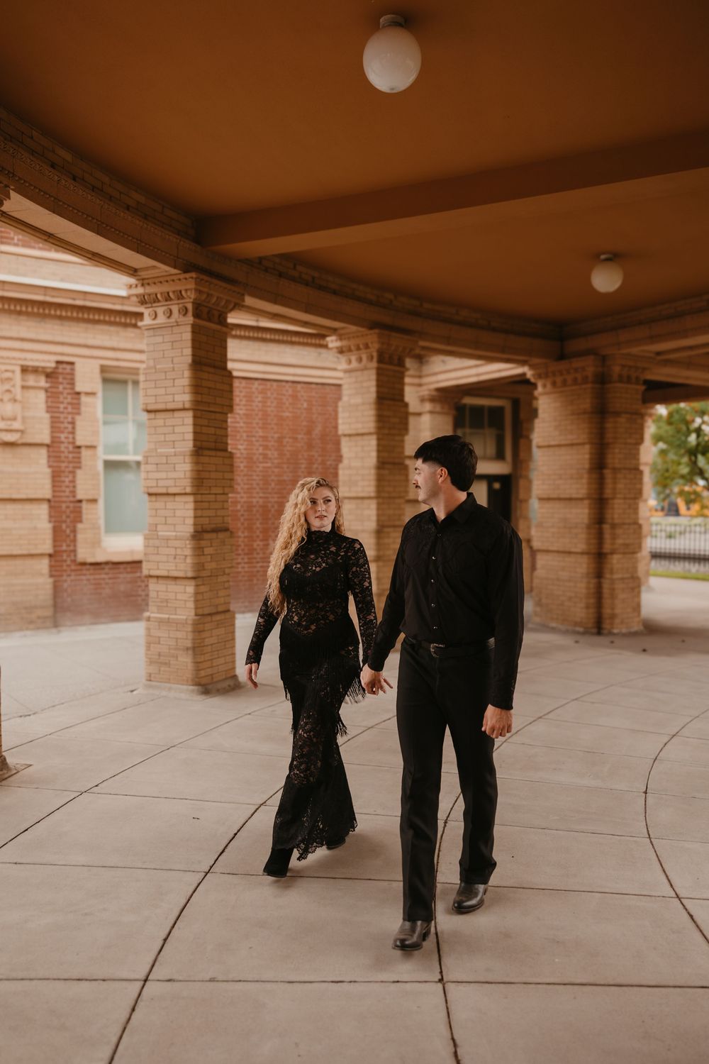 Couple walks together under the historic train station in Livingston, Montana captured by local Paradise Valley Wedding Photographer