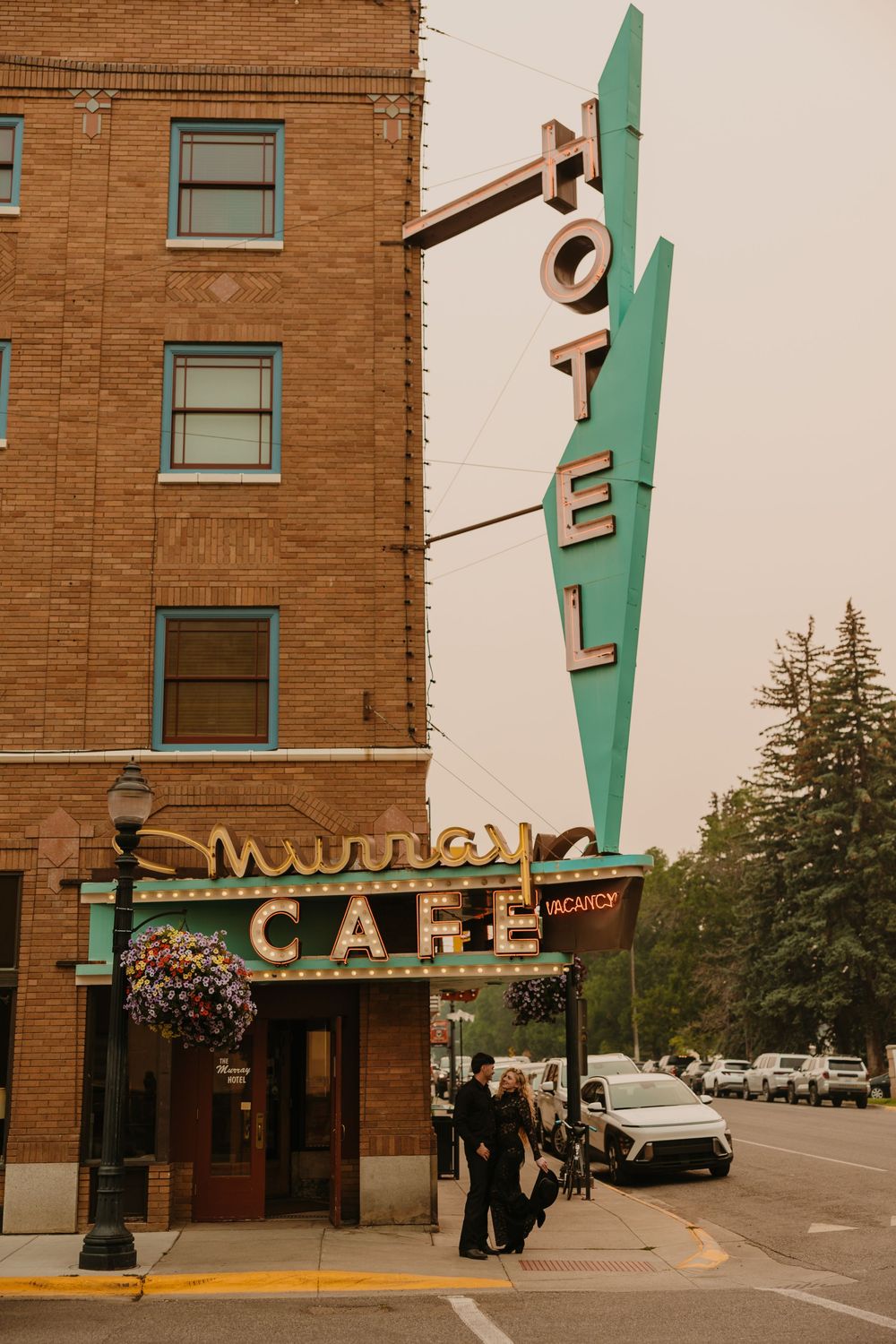 Couple poses under the Murray Hotel Neon light signs for their welcome party pre-wedding - Livingston Wedding Photographer - Montana Bride