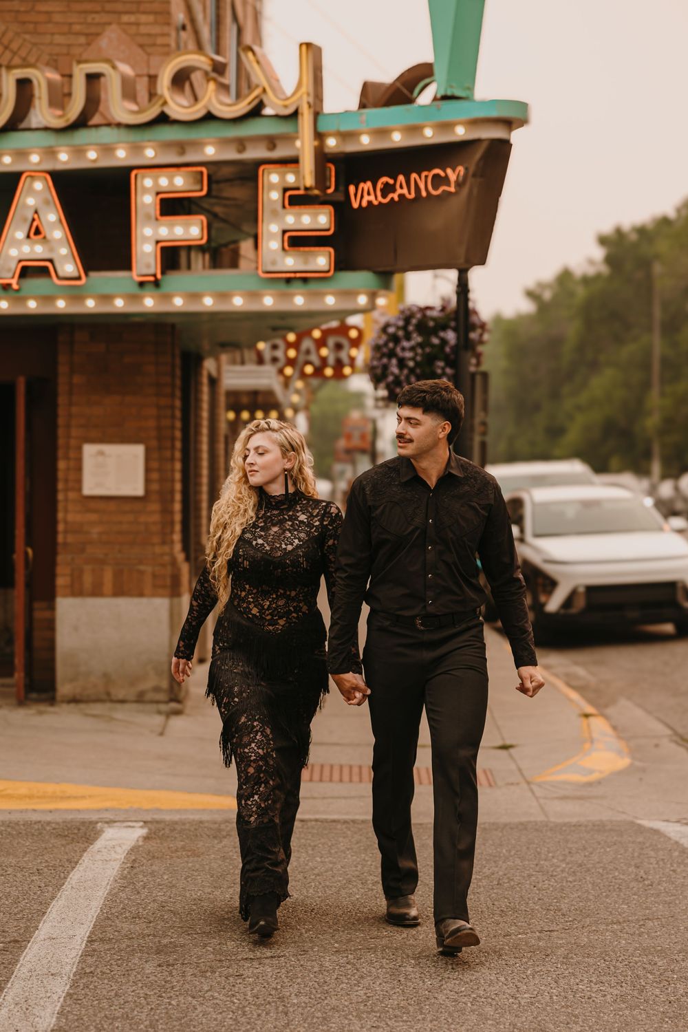 Couple poses under the Murray Hotel Neon light signs in Livingston, Montana for their welcome party. Livingston Wedding Weekend Photographer