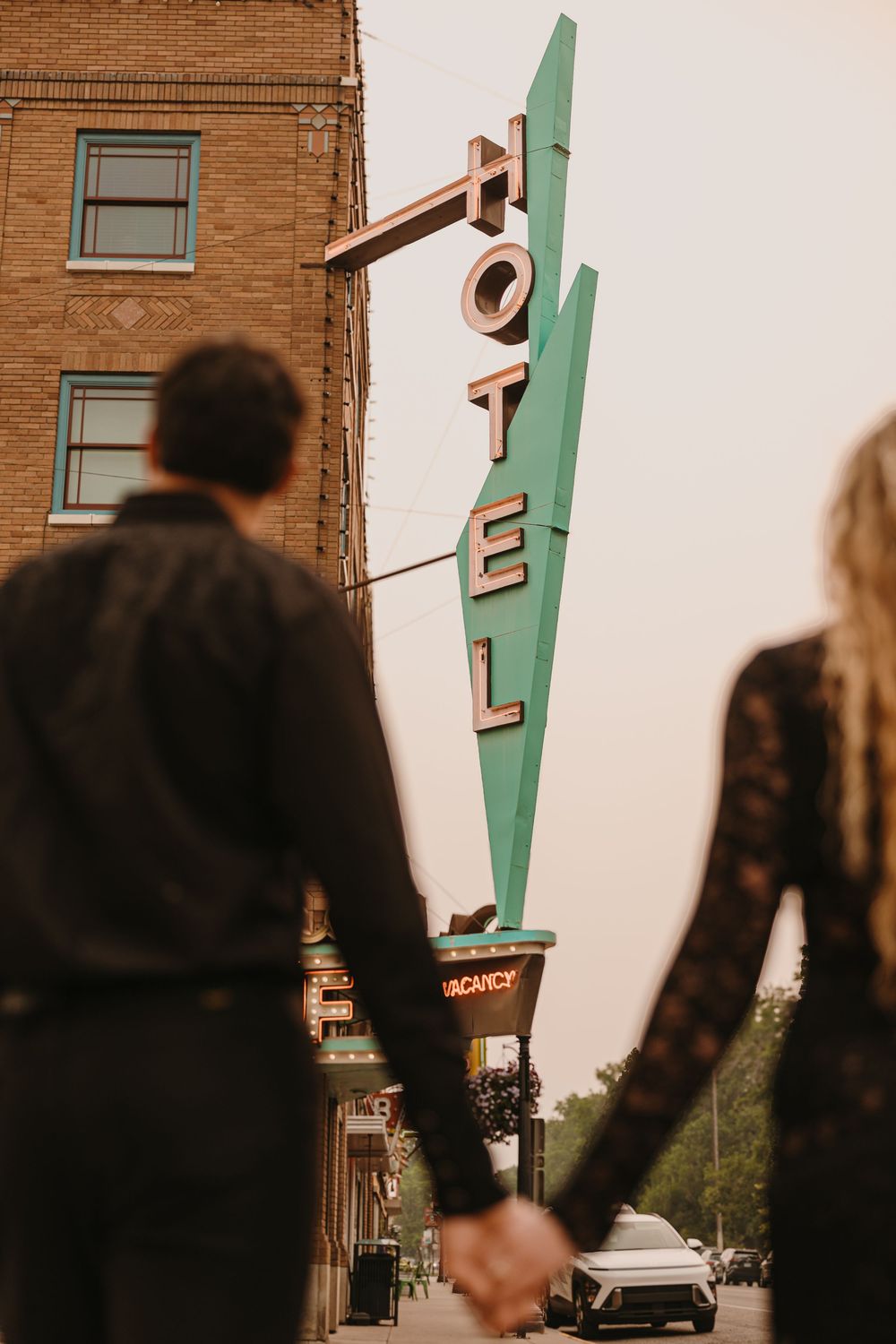 Couple poses under the Murray Hotel Neon light signs in Livingston, Montana for their welcome party - Paradise Valley Wedding Photographer