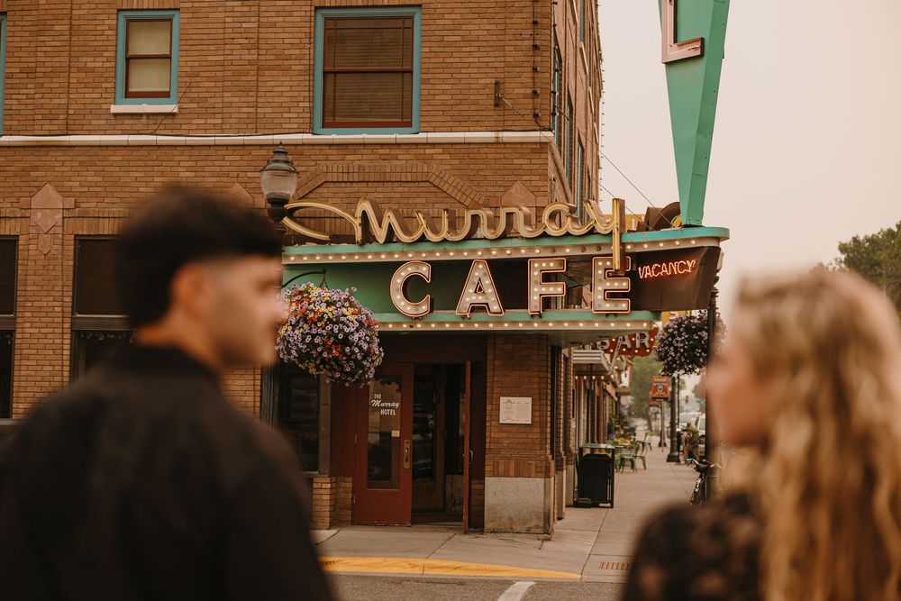 Couple poses under the Murray Hotel Neon light signs in Livingston, Montana for their welcome party - Paradise Valley Photographer