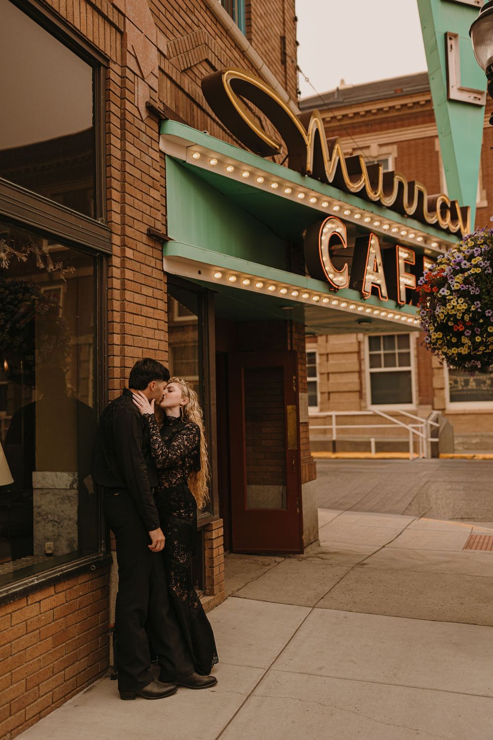 Couple poses under the Murray Hotel Neon light signs in Livingston, Montana for their welcome party pre-wedding - Livingston Photographer