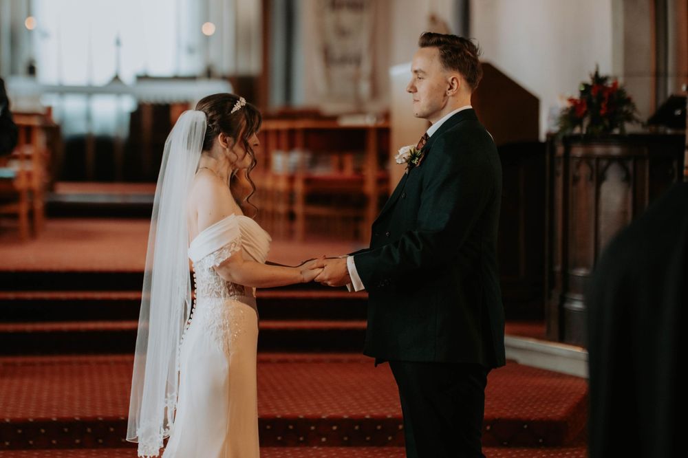 A bride and groom holding hands at the altar during their church wedding ceremony.
