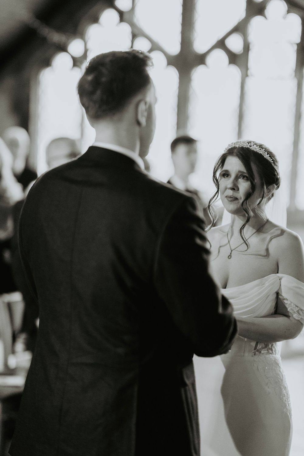 Bride gazing emotionally at groom during wedding ceremony vows in a stunning church setting.