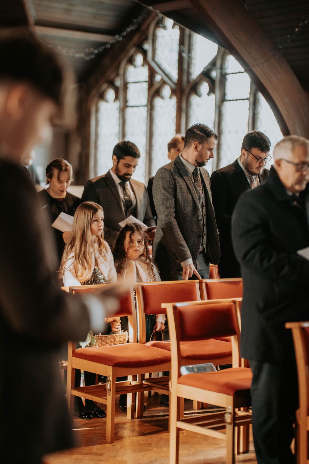Wedding guests standing in historic church pews during ceremony service.