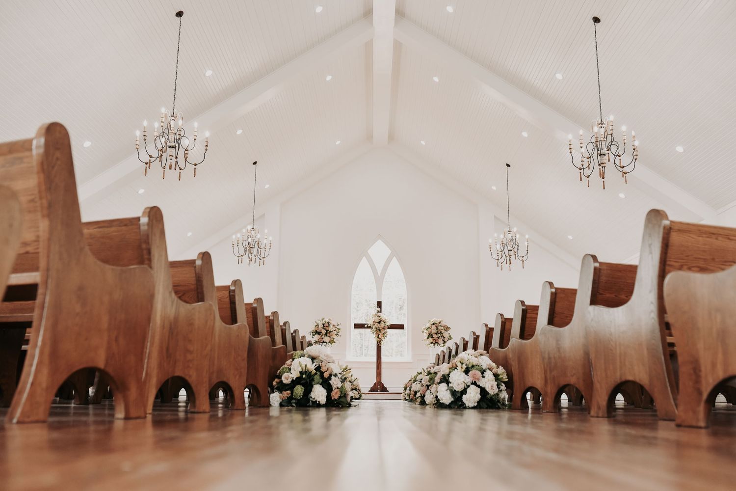 White shiplap wedding chapel decorated with blush pink, mauve and ivory flowers