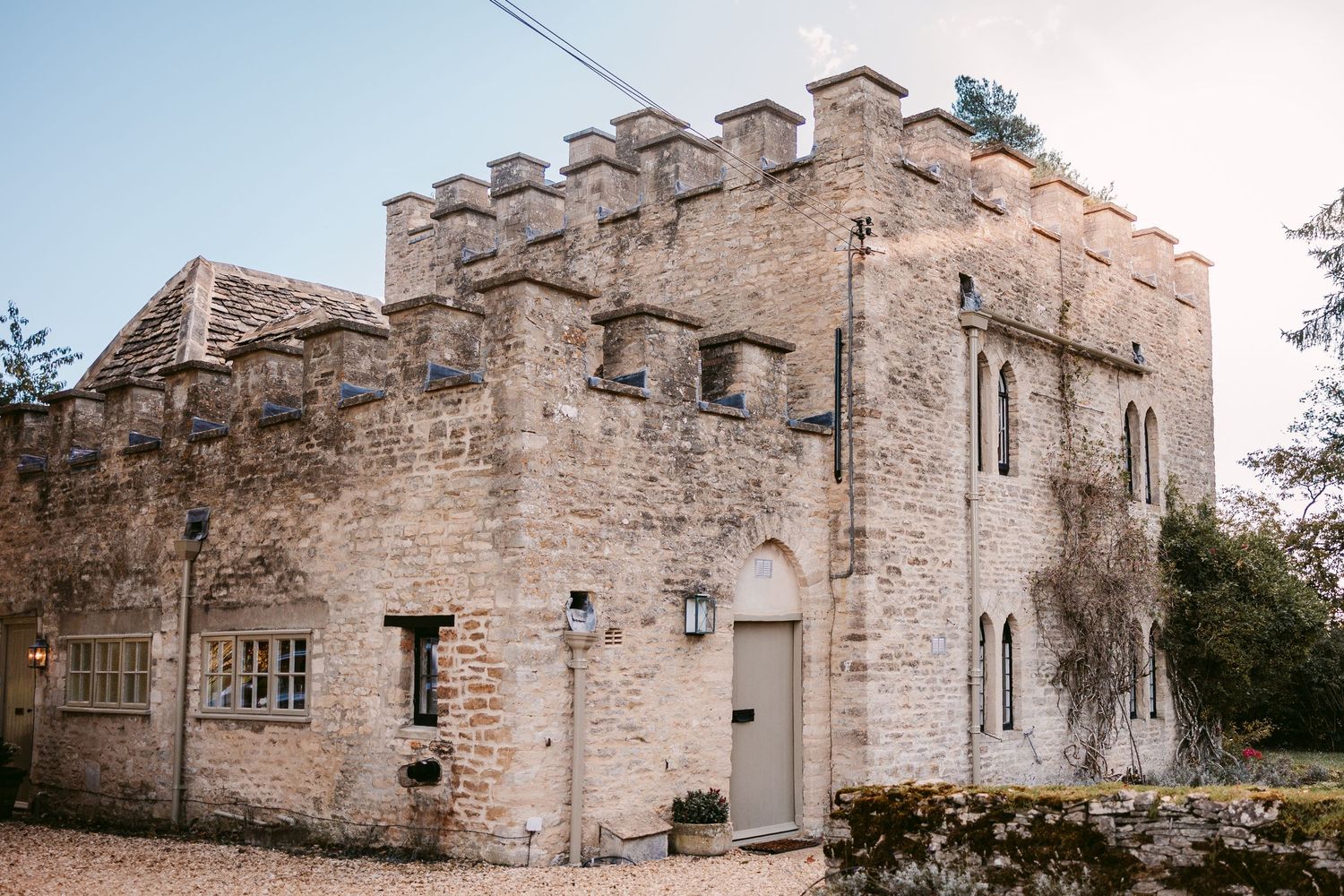 Exterior of a historic castle-style stone wedding venue with battlements, arched windows and a wooden door.
