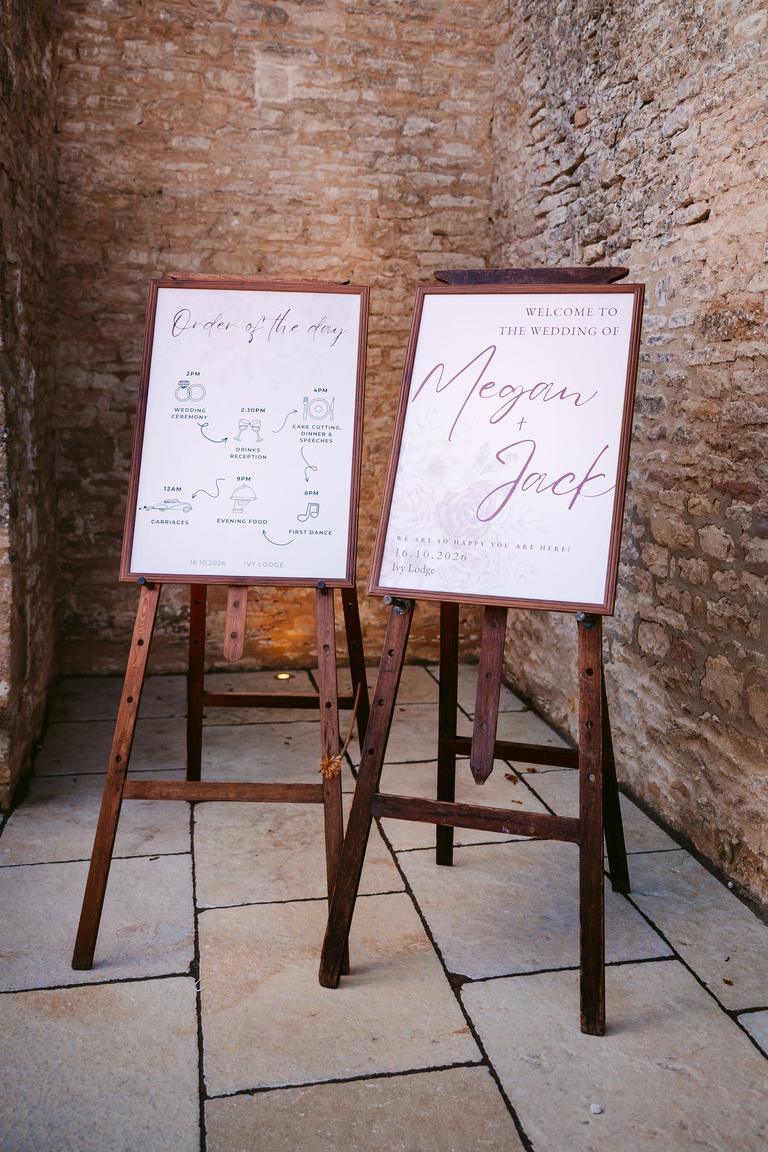 Two wooden easels in a stone-walled venue display a wedding welcome sign for Megan and Jack and an order of the day sign.