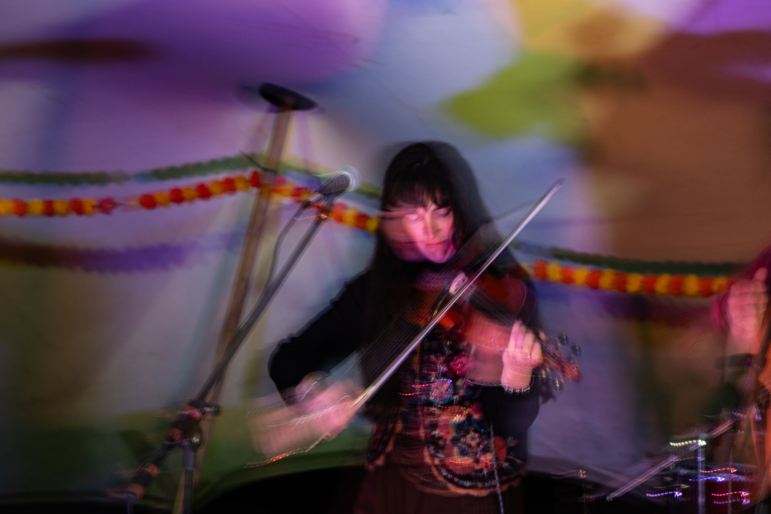 A female violinist performs on stage with colorful decorations and dramatic motion blur lighting effects.