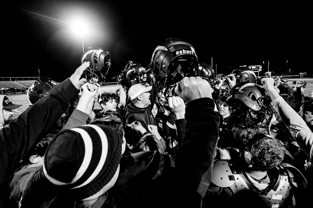 A crowd of photographers with cameras raised capturing a night event in black and white.