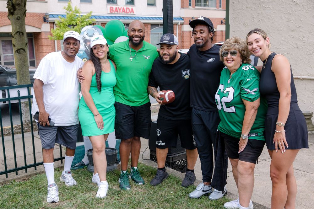 Group in green and white athletic wear gather for a casual outdoor photo.