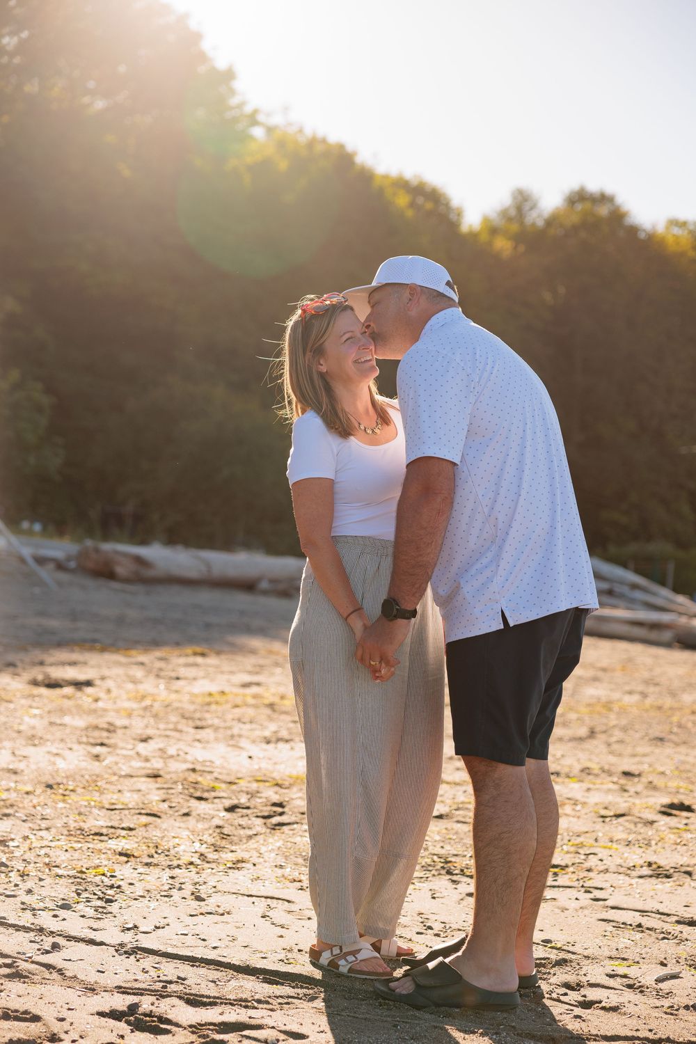 Couple sharing a romantic moment on a sunny beach at golden hour, holding hands and laughing together.
