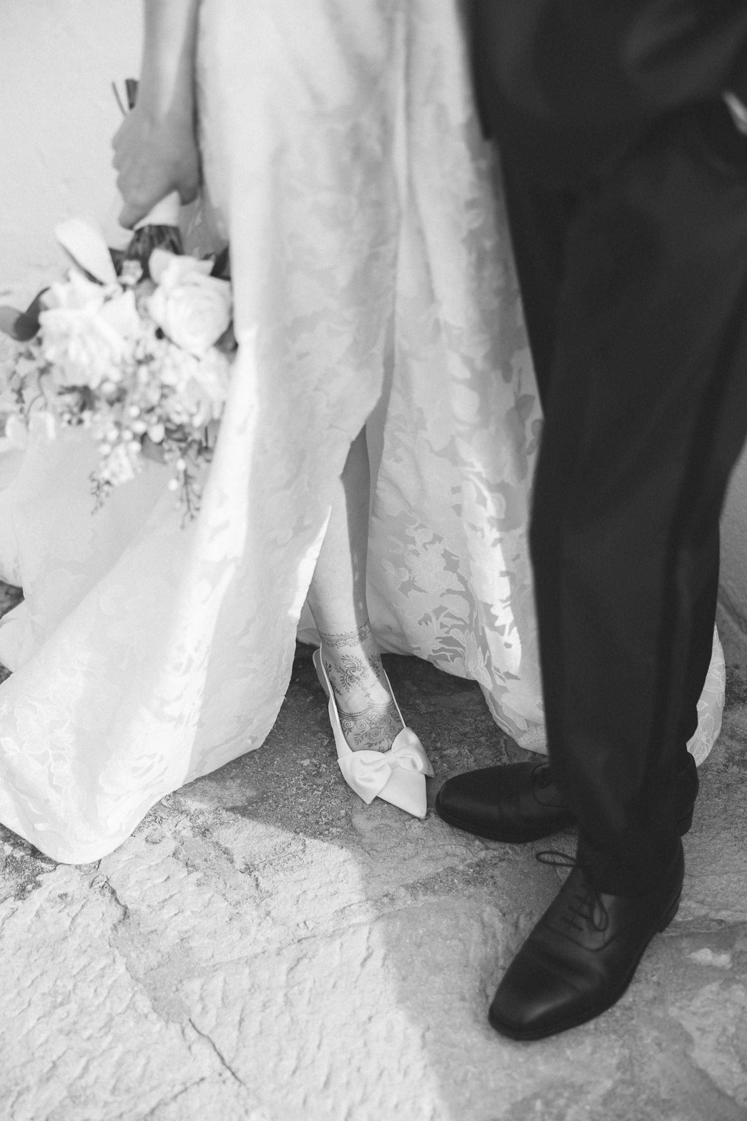 Artistic black and white detail of the bride's wedding shoes, bouquet and gown before an elegant destination wedding in Portugal.