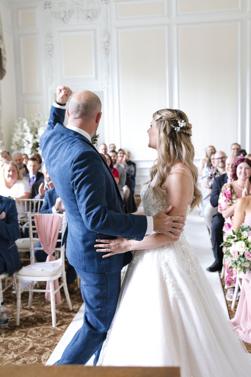 Bride and groom sharing a joyful first dance at their elegant wedding ceremony surrounded by seated guests.