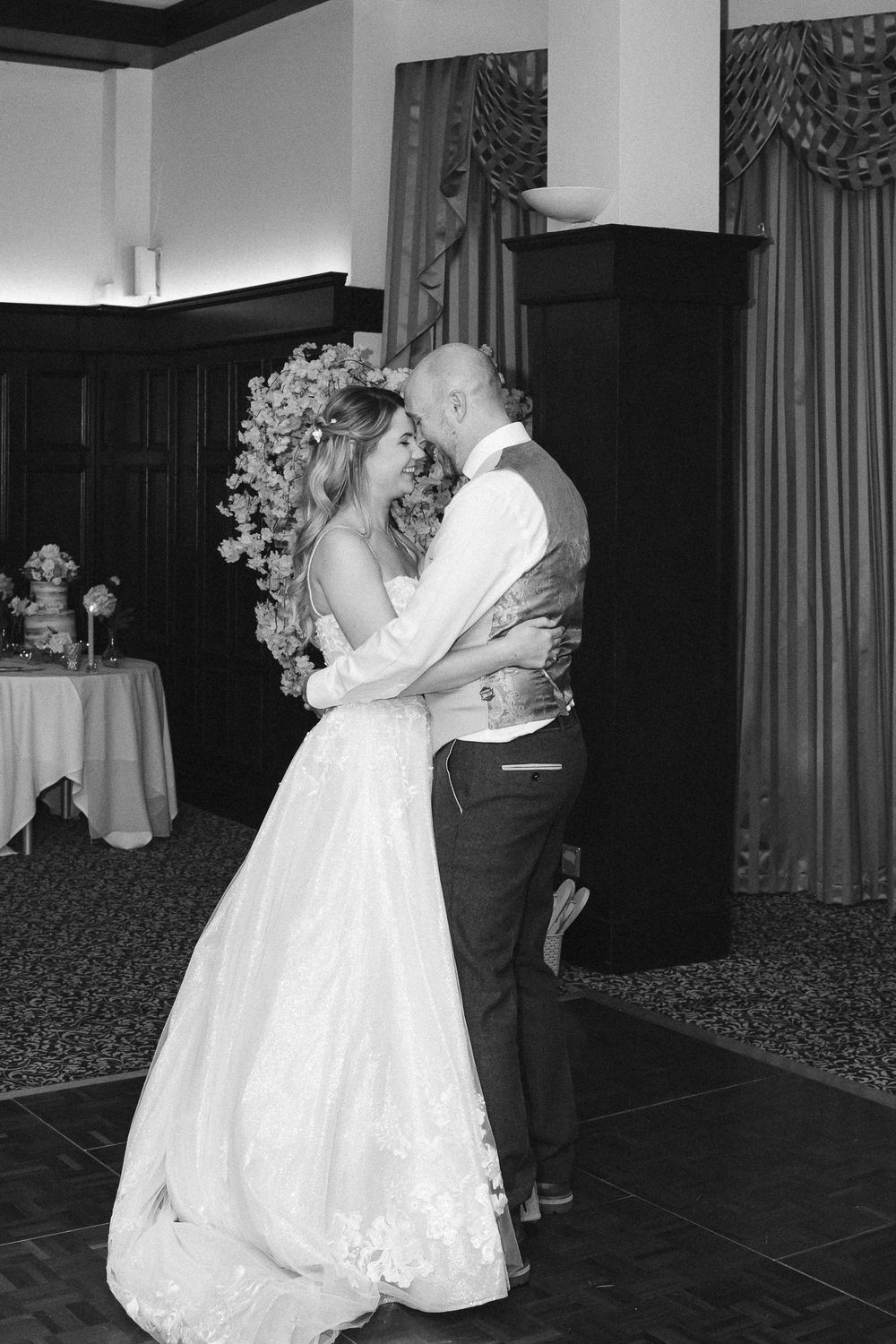 Bride and bald groom share intimate first dance in elegant wedding reception venue.