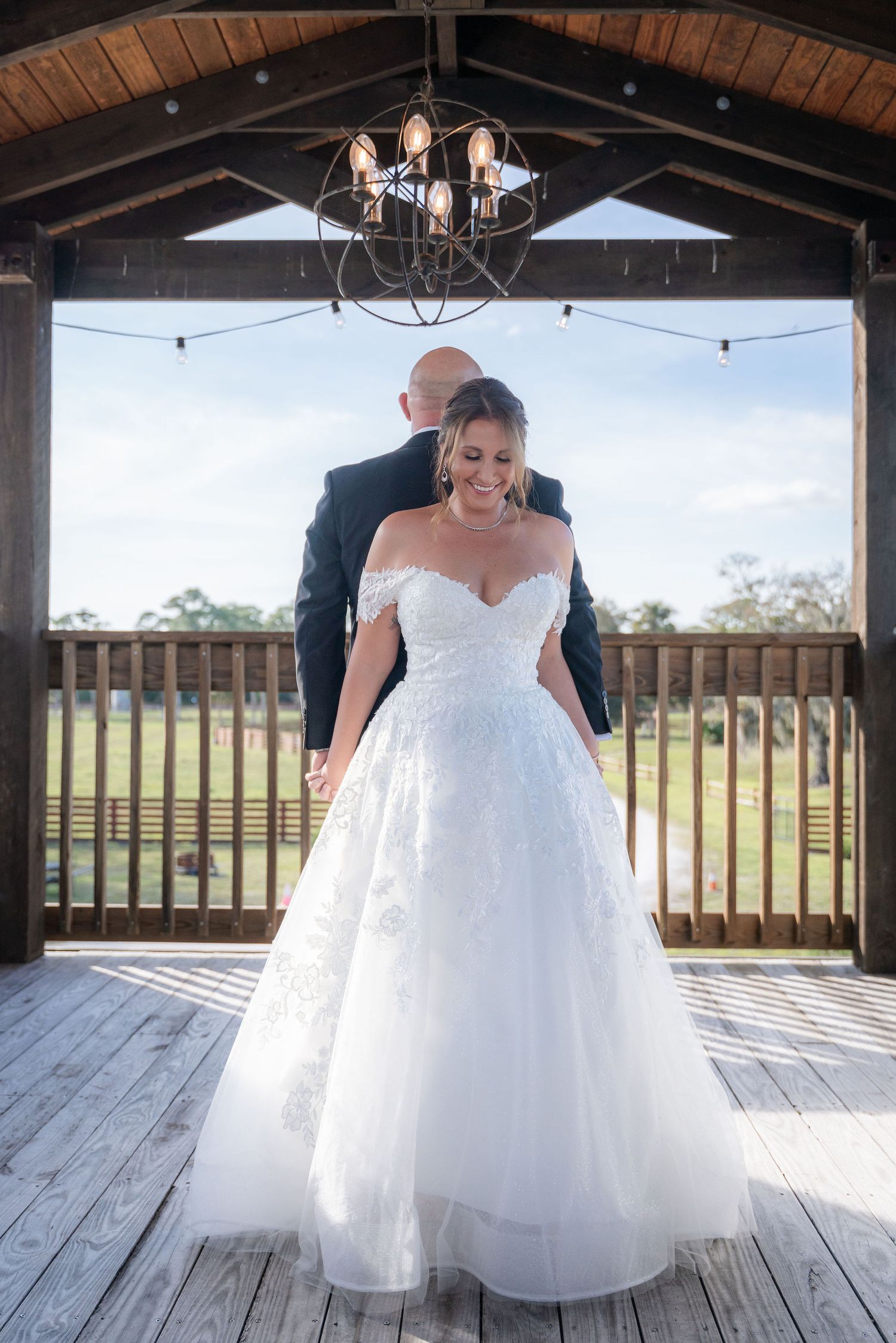 Bride and groom holding hands back to back for a first touch on the covered balcony at Rockin' H Ranch, Palm City FL